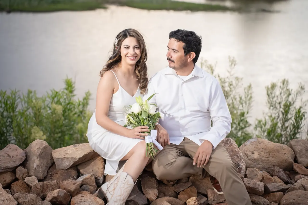 Analhy y Alejandro sentados junto al lago con el ramo de novia